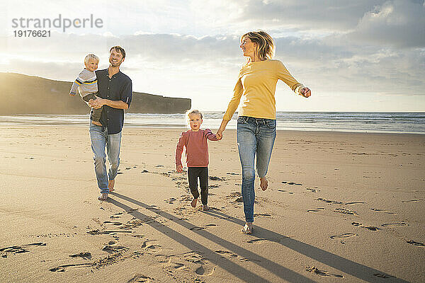 Lächelnder Vater und Mutter  die Spaß mit Kindern am Strand haben