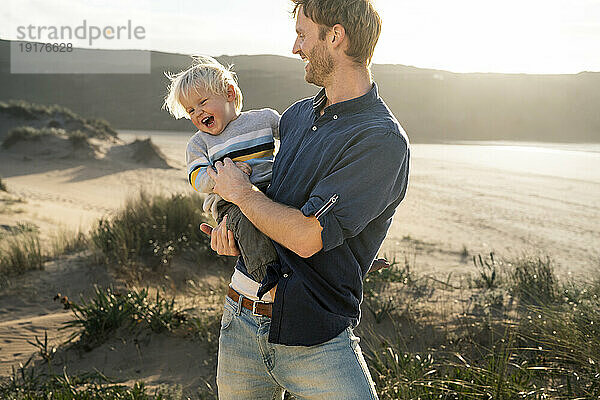 Fröhlicher Vater und Sohn genießen einen sonnigen Tag am Strand