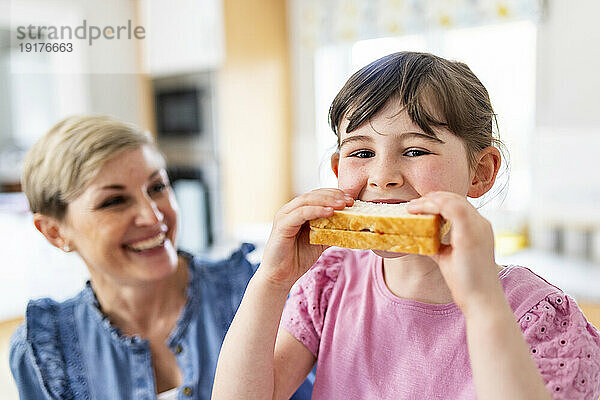 Mädchen isst Sandwich von der Mutter zu Hause