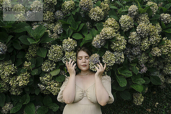 Schöne Frau steht vor Hortensienpflanzen im Garten
