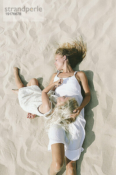 Mother and daughter relaxing on sand at beach