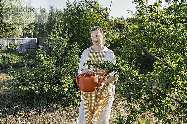 Gärtner mit Gießkanne steht im Garten