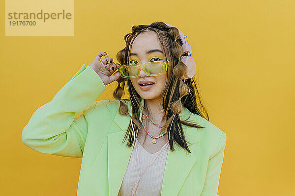 Junge Frau mit Kopfhörern und Sonnenbrille im Studio