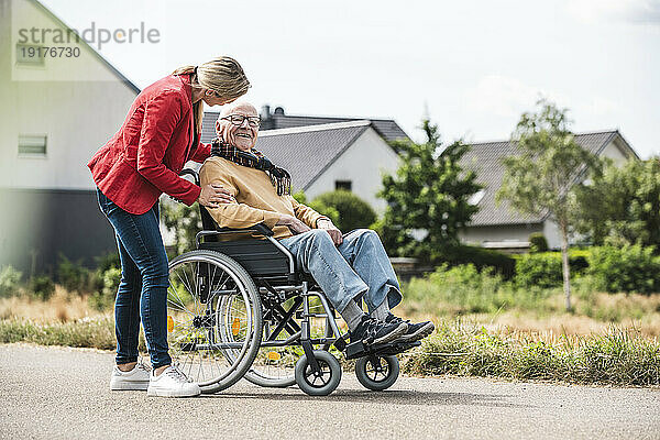 Frau spricht mit älterem Mann im Rollstuhl