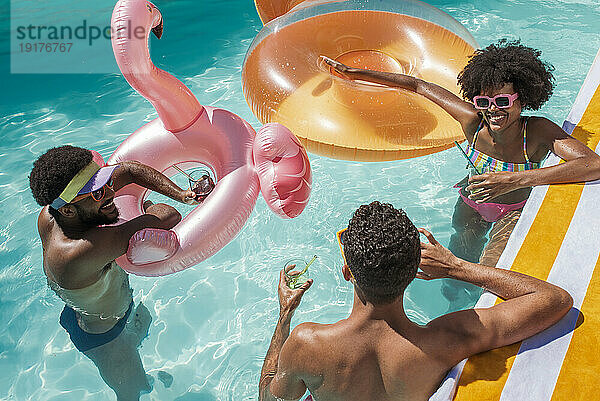 Glückliche Freunde mit aufblasbaren Schwimmkörpern  die im Pool Spaß haben
