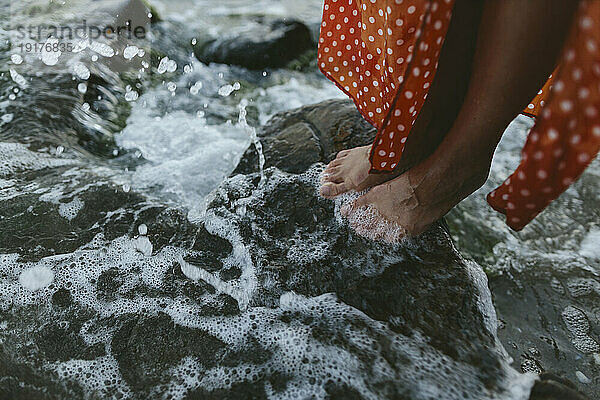 Frau steht auf Felsen im Meer