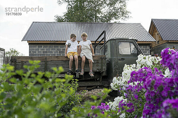 Glückliche Jungs sitzen auf einem alten Lastwagen im Garten