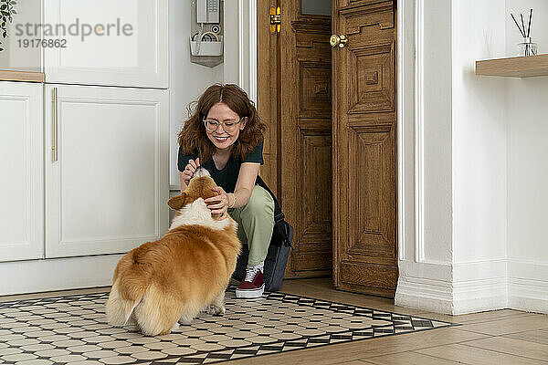 Lächelnde Frau streichelt Hund  der zu Hause sitzt