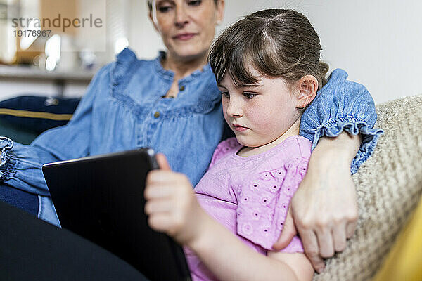 Mädchen benutzt Tablet-PC von Mutter im Wohnzimmer