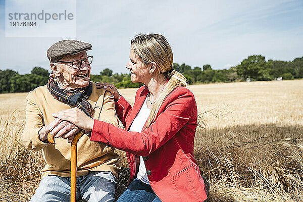 Fröhlicher älterer Mann  der an einem sonnigen Tag mit einer Frau auf dem Feld spricht