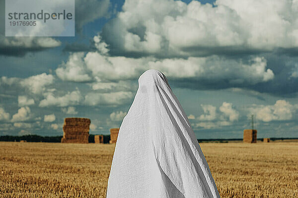 Frau im Geisterkostüm steht im Weizenfeld