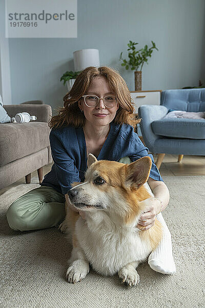 Frau mit walisischem Corgi-Hund sitzt im Wohnzimmer