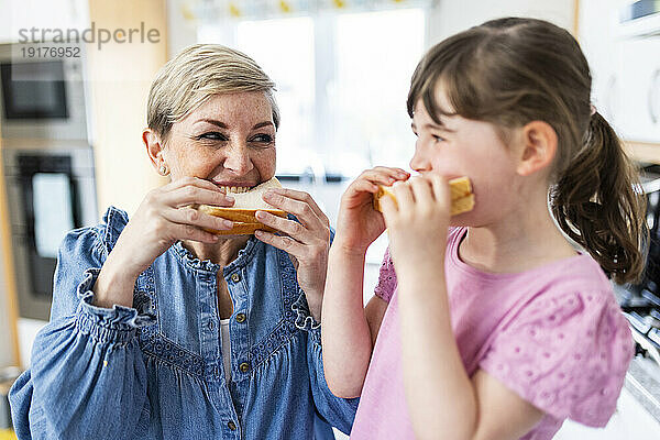 Mutter und Tochter essen Sandwiches in der Küche