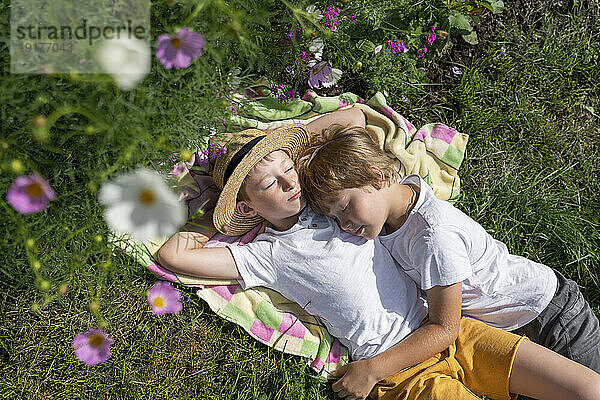 Jungen entspannen sich an einem sonnigen Tag auf einer Decke im Garten