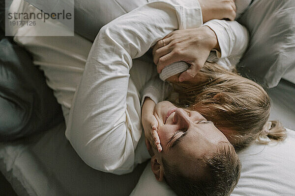 Smiling father hugging daughter in bed at home