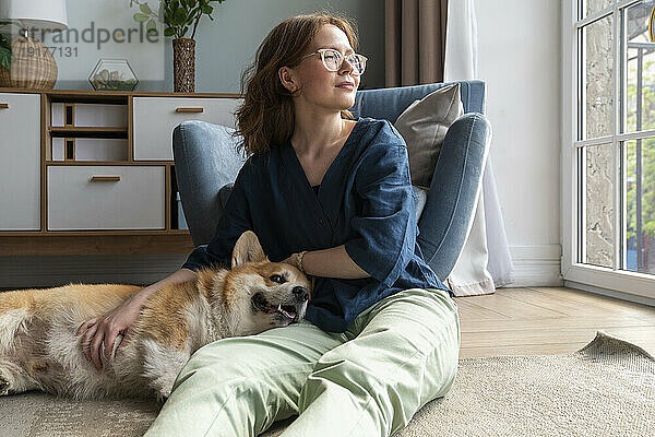 Welsh Corgi dog resting on woman's lap in living room