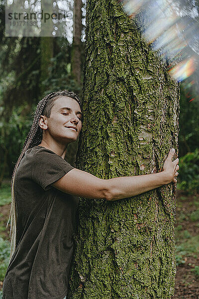 Frau umarmt Baum im Wald