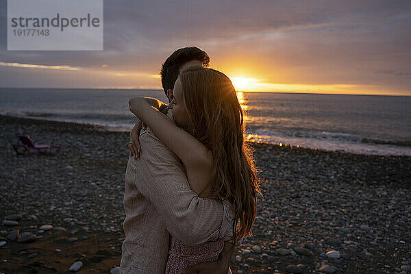 Junges romantisches Paar umarmt sich am Strand