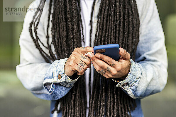 Mann mit langen Haaren benutzt Smartphone