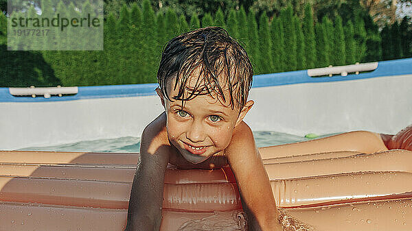 Netter Junge mit Schwimmkörper genießt den Sommer im Hinterhof