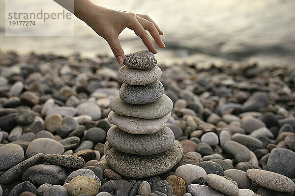 Hand of woman stacking pebbles at beach