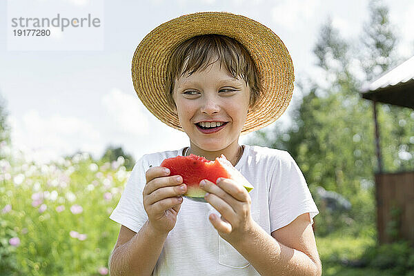 Smiling boy standing with slice of watermelon
