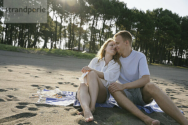 Romantisches Paar sitzt an einem sonnigen Tag am Strand