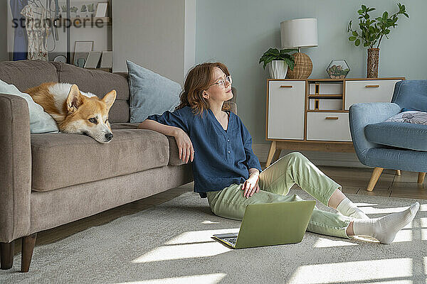 Nachdenklicher Freiberufler mit walisischem Corgi-Hund auf dem heimischen Sofa