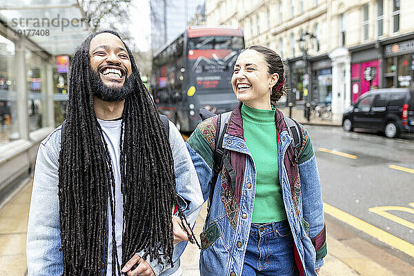 Happy multiracial couple walking at footpath