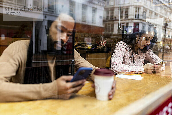 Mann und Frau benutzen Smartphone im Café