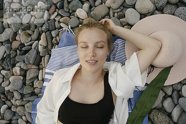Junge Frau liegt auf Kieselsteinen am Strand
