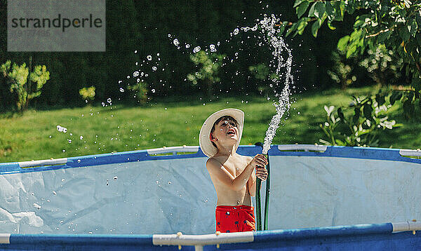 Netter Junge spielt mit Wasserpfeife im Schwimmbad