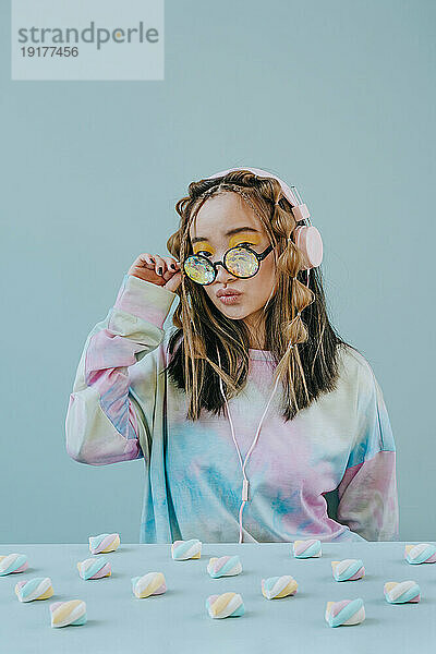 Junge Frau mit Marshmallows auf dem Tisch und Kaleidoskopbrille im Studio