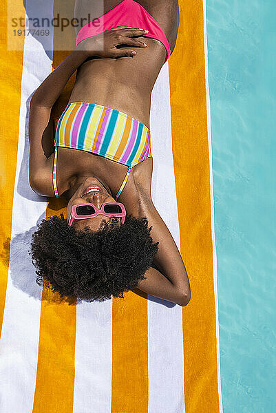 Happy woman wearing sunglasses lying on towel