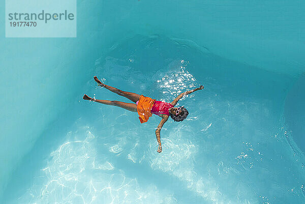 Young woman wearing sunglasses swimming in pool