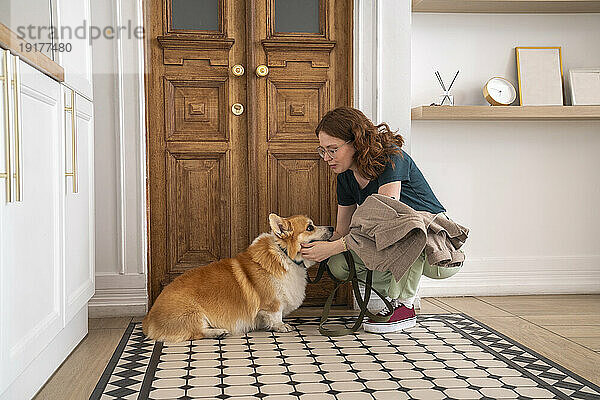 Frau streichelt Hund  der zu Hause auf Teppich sitzt
