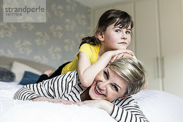 Daughter leaning on mother lying down at home