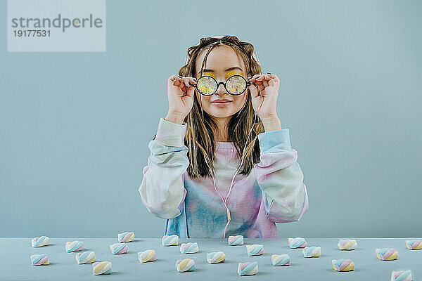 Frau mit Kaleidoskopbrille am Tisch mit Marshmallows im Studio