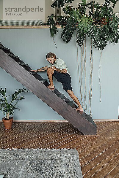 Young man exercising on staircase at home