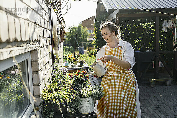 Frau gießt an sonnigem Tag Pflanzen im Garten