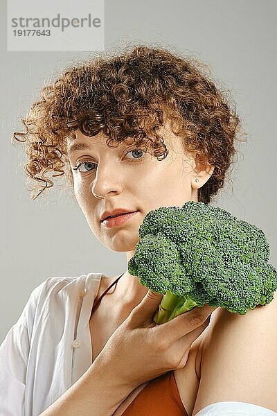 Nette junge Frau hält Brokkoli in der Hand. Konzept der gesunden Ernährung
