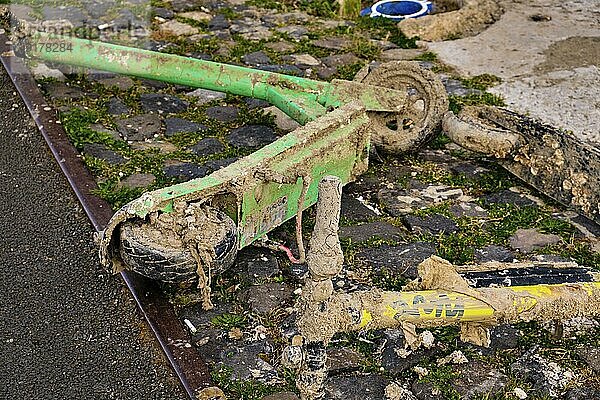 Aus dem Wasser geborgene  mit Schlamm und Müll bedeckte Kicksharing Elektroroller  die am Ufer liegen. Ökologische Bedrohung  Mikromobilität  Umweltverschmutzung  kommunales Problem  Verbot  Giftmüll. Selektiver Fokus  unscharfer Hintergrund. Lissabon  Portugal  Europa