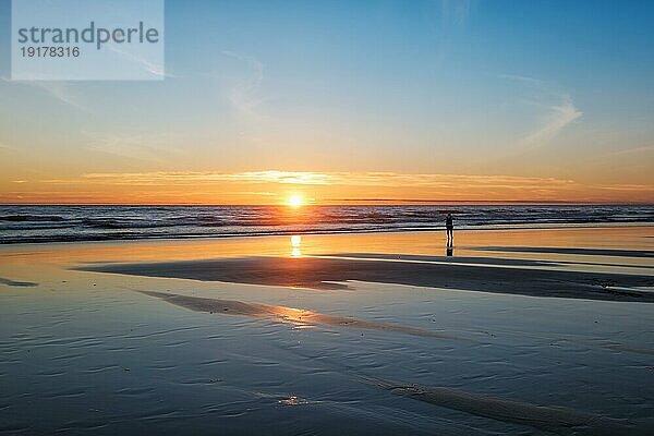 Sonnenuntergang über dem Atlantik mit der Silhouette eines Fotografen  der am Strand von Fonte da Telha  an der Costa da Caparica  Portugal  Bilder von der Brandung macht  Europa