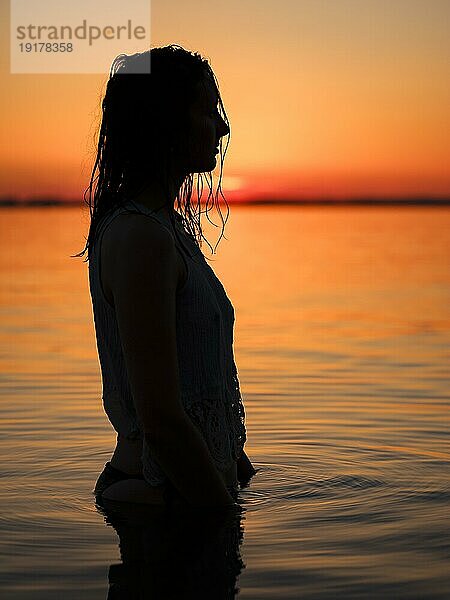 Silhouette einer jungen Frau im Wasser bei Abenddämmerung  Chiemsee  Chiemgau  Oberbayern  Bayern  Deutschland  Europa