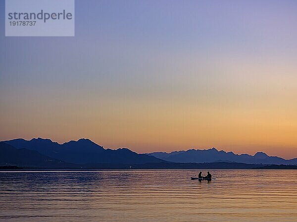 Zwei Personen sitzen auf ihrem Board im Wasser bei Abenddämmerung  hinten die Chiemgauer Alpen  Chiemsee  Chiemgau  Oberbayern  Bayern  Deutschland  Europa