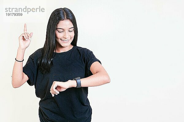 Glückliches lateinamerikanisches Mädchen  das auf eine Handuhr schaut. Lächelnde Teenagermädchen Blick auf Hand Uhr isoliert