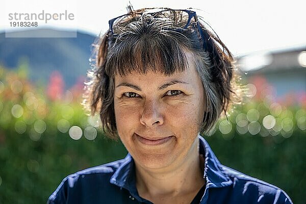 Headshot einer glücklich lächelnden Frau mit Brille an einem sonnigen Tag in der Schweiz