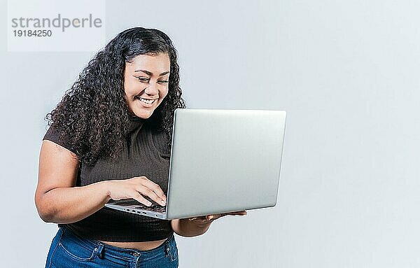Lächelnde lateinischen Menschen suchen Angebot promo auf Laptop isoliert. Überrascht Mädchen Blick auf eine Förderung auf Laptopbildschirm isoliert. Erstaunt lateinische Frau mit Laptop