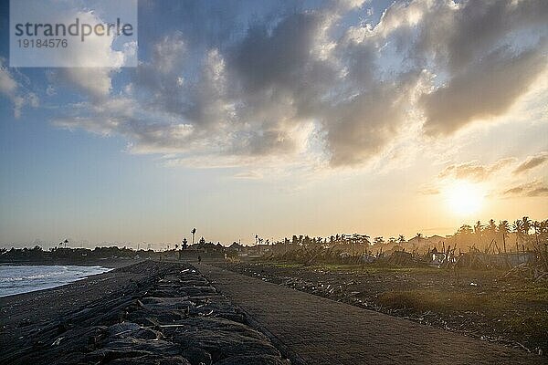 Schwarzer Sandstrand auf Bali  natürlich mit Tempeln  Booten (Jukung) und Wellen im Sonnenuntergang. Tropische Umgebung in Indonesien