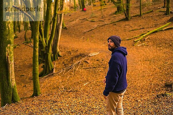 Lifestyle  ein lächelnder junger Mann in blauem Wollpullover und Hut genießt den Wald im Herbst. Artikutza Wald in San Sebastián  Gipuzkoa  Baskenland. Spanien